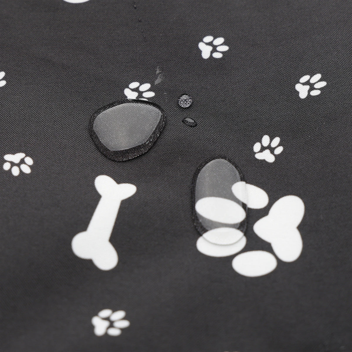 Close-up of water droplets on black fabric printed with white paws and bones, from a portable dog car seat